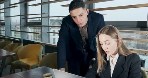 Portrait of a Man and a Woman Discussing Work with Notebook in the Brightly Lit Modern Office