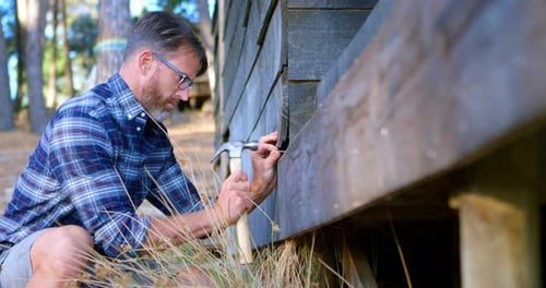 Man hammering wooden plank with hammer 4k
