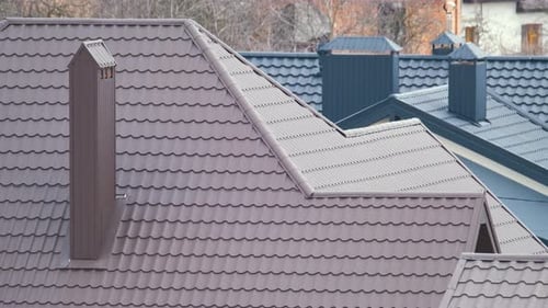 Chimney on House Roof Top Covered with Metallic Shingles Under Construction