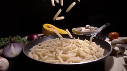 Uncooked Penne Pasta Falling into Frying Pan