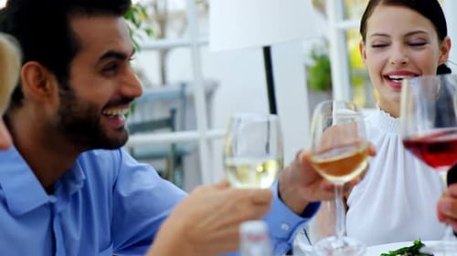 Friends interacting with each other while having glass of wine