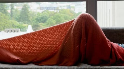 Woman Relaxing with Smartphone on Sofa Under Blanket