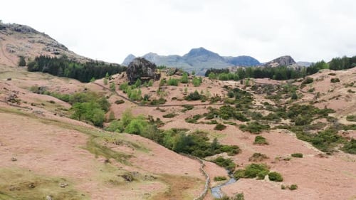 Aerial View Over Hills Towards Mountains