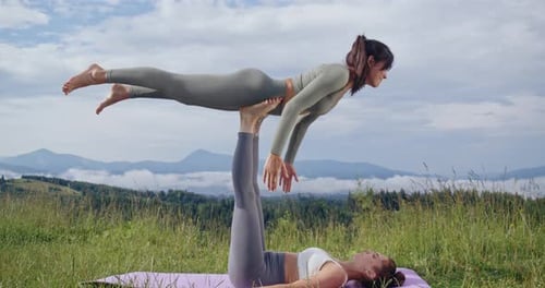 Women Doing Acroyoga on Grassy Field in the Mountains