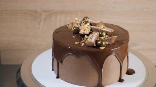 Chocolate Cake with Glaze, Peanuts and Chocolate Pieces Rotates on the Rotating Stand