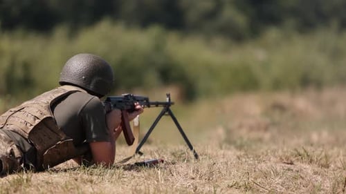 Soldier Lies Prone and Fires Rifle in Field