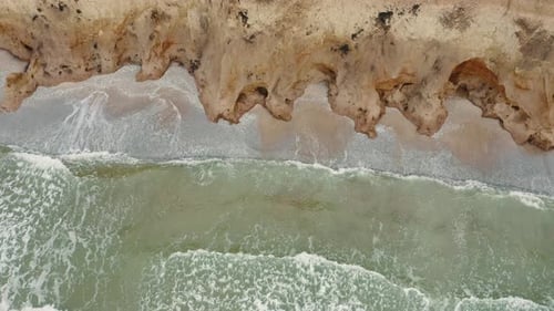 Aerial View of Waves Beating Against a Rocky Shore on a Sandy Tropical Beach
