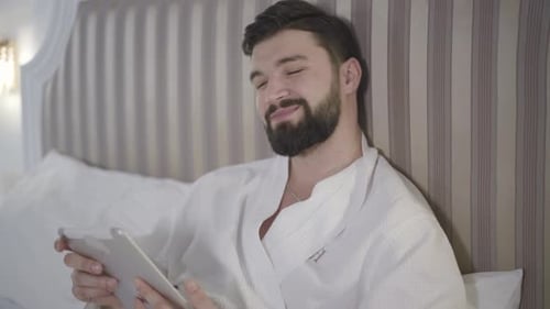 Close-up Portrait of Thoughtful Caucasian Man Using Tablet and Smiling