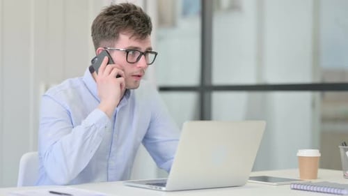 Young Man Talking on Phone at Desk