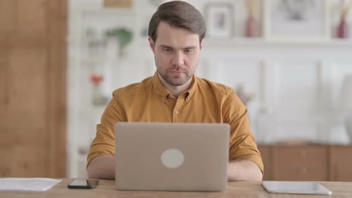 Young Man Celebrating Success while using Laptop in Office