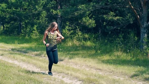 Young Girl Goes in for Sports in the Morning, Runs Along a Pine Forest.