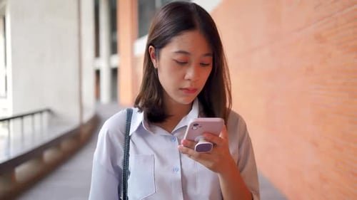 A woman using a modern phone walking down the street.