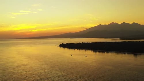 romantic aerial landscape, open ocean small island with mountains in the beautiful golden light of t