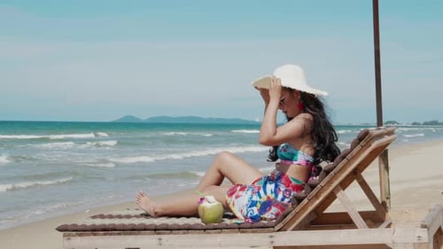 Woman in bikini lying on lounge chair on tropical beach sun tanning Vacation summer travel concept