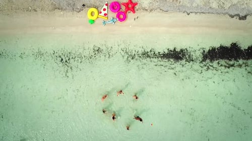 Aerial view of friends playing volleyball standing in sea by sandy beach.