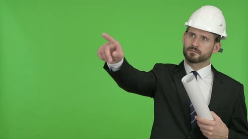 Ingenieur mit Blueprint zeigt mit dem Finger gegen Chroma-Key