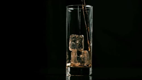Amber Liquid Being Poured into Glass with Ice
