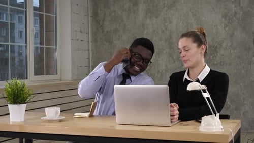 Colleagues Collaborate at Desk in Modern Office