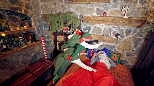 Le Père Noël dort dans une chambre spécialement décorée dans son lit. La main sous la joue.
