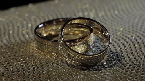 Gold Wedding Rings on Sparkling Gold Surface
