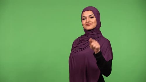 A Young Beautiful Muslim Woman Points at the Camera and Nods with a Smile Green Screen Background