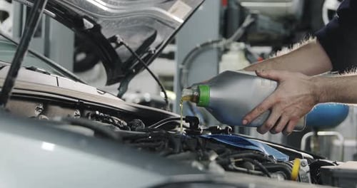 Mechanic Refilling Car with Engine Oil