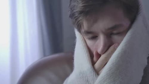 Gros plan extrême d'un garçon caucasien malade qui tousse et se frotte les yeux. Portrait d'un malade caucasien fatigué