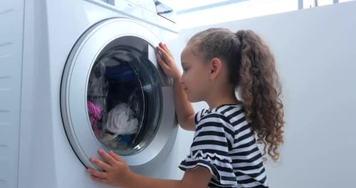 Nettes Kind schaut in die Waschmaschine