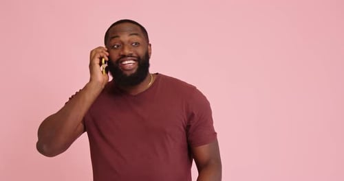 Young African American Man Talk on Phone Isolated on Pink Background