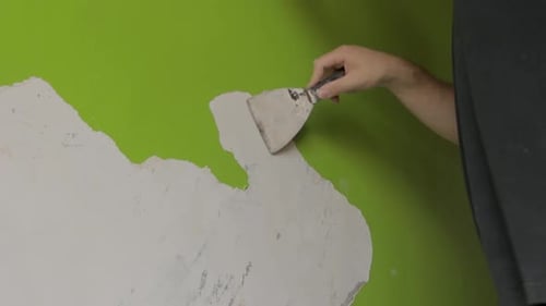 plano amplio y estable de un hombre raspando pintura verde de una pared