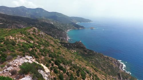 Aerial View of Rocky Coastline with Green Bushes Down Blue Sea