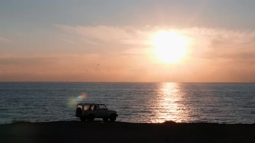 Beach Sunset with Car Silhouette Over the Ocean