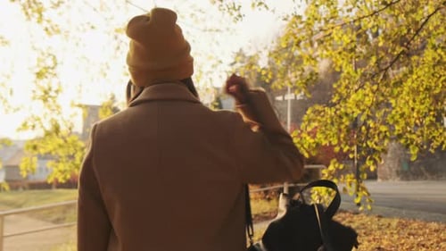 Woman Waving Down Avenue in City During Autumn