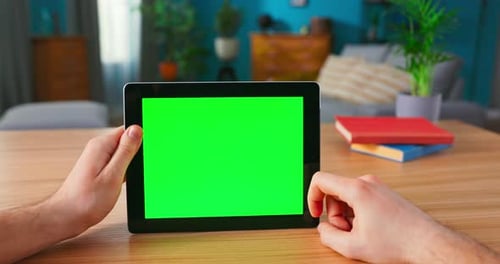 Man Holding and Using Hand Gestures on Green Mockup Screen Digital Tablet Computer While Sitting