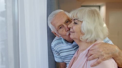 Senior Couple Affectionately Embracing Looking out of Window
