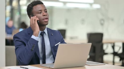 Young Adult Man Talking on Cellphone at Desk