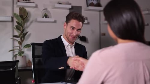 Man Talking to Woman and Shaking Hands During Job Interview at Table in Modern Office Spbi