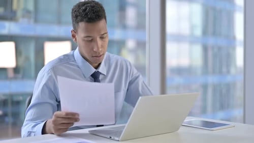 African American Businessman Reading Document in Office