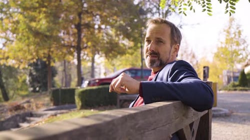 Man Relaxing on Bench in Sunny Autumn Park
