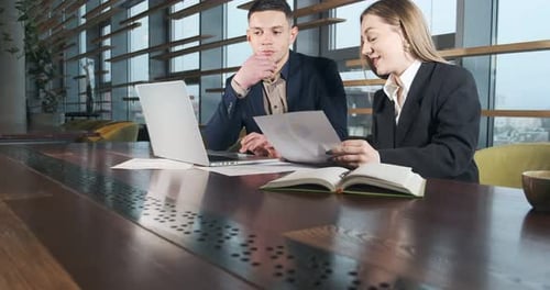 Man and a Woman Discussing Work in the Brightly Lit Modern Office. Concerned Male and Female Working