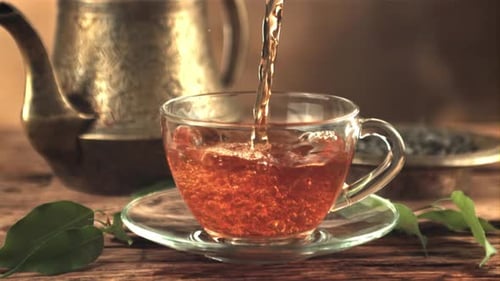 Ein Teestrahl in Superzeitlupe fließt in eine Tasse mit Luftblasen
