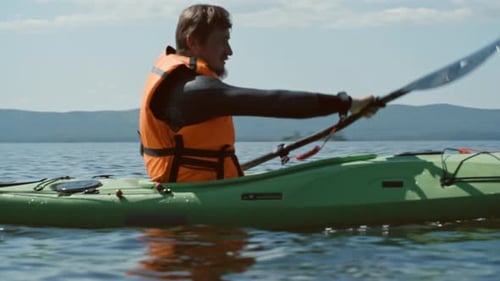 Man Paddles Kayak on Tropical Lake