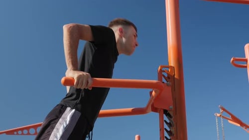 Sport. Fitness. Mann führt Liegestütze an unebenen Stangen
durch