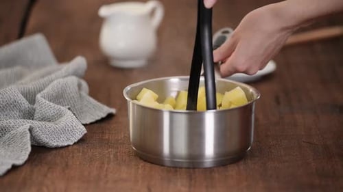 Mashing Cooked Potatoes in Stainless Steel Pot