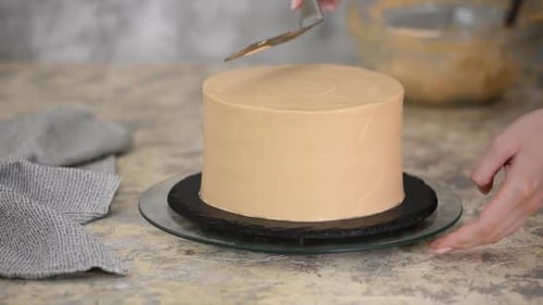 Icing a cake with smooth beige frosting