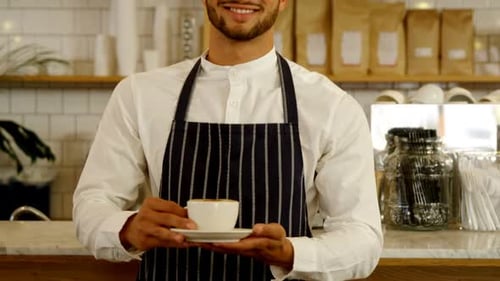 Smiling Barista Holds a Cup of Coffee