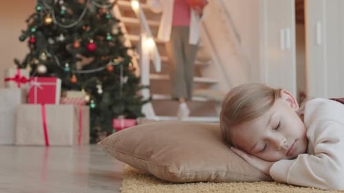 Child Sleeping by Christmas Tree while Woman Delivers Gifts