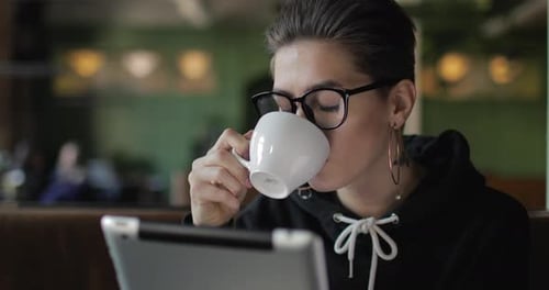 Woman Using Tablet at Cafe Drinking Coffee