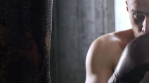 Man Punches Heavy Bag Wearing Boxing Gloves