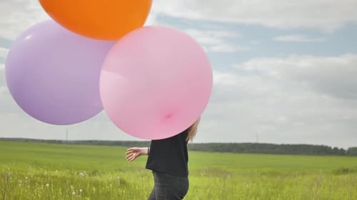 Happy Girl with Big Multicolored Balloons Posing on the Field